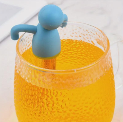 Premium tea ball infuser placed next to loose tea leaves and a cup

